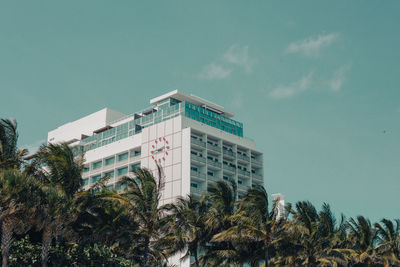 Low angle view of palm trees and building against sky