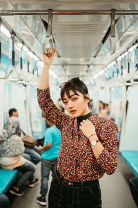 Portrait of young woman standing in train