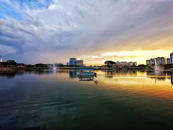 Scenic view of river by buildings against sky during sunset