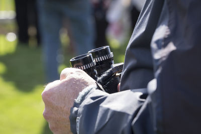 Midsection of man holding binoculars while standing outdoors