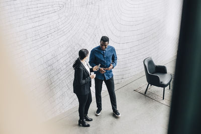 High angle view of business people talking while standing against wall at office conference