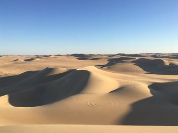 Sand dunes in desert against clear sky