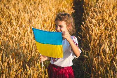 Girl holding ukrainian flag in field