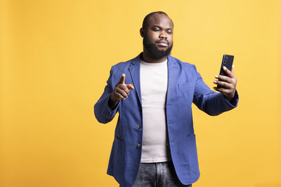 Young man using mobile phone against blue background