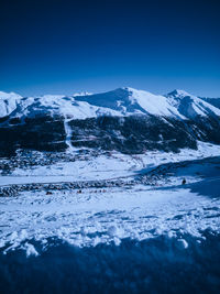 Scenic view of snowcapped mountains against clear blue sky