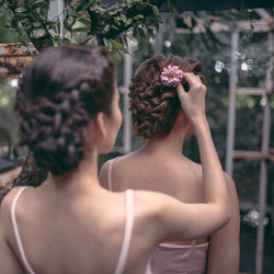 Rear view of woman adjusting flower on bride hair