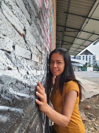 Portrait of beautiful woman standing against brick wall