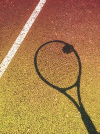 Shadow of tennis racket with ball on court