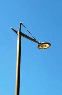 Low angle view of telephone pole against clear blue sky