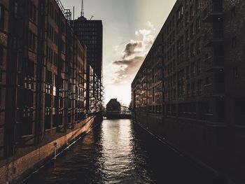 Canal amidst buildings in city against sky