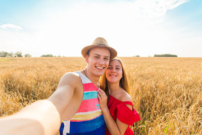 Portrait of smiling young woman on field against sky