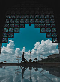 Digital composite image of silhouette man standing by building against sky