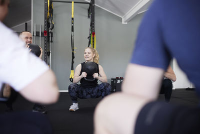 Smiling people exercising with kettlebells in gym