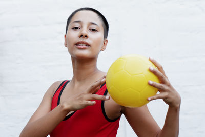 Portrait of young woman holding soccer ball at beach