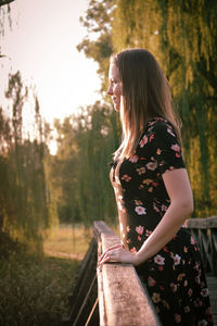 Side view of woman standing by railing