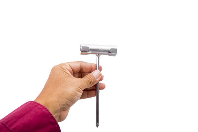 Close-up of hand holding metal against white background