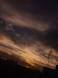 Low angle view of silhouette telephone pole against sky during sunset