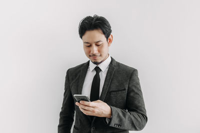 Young man using smart phone against white background