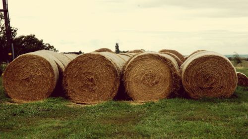 Hay bales on field against sky