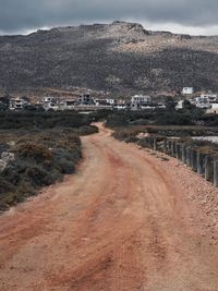 Road amidst buildings in town against sky