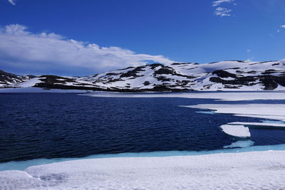 Scenic view of sea by snowcapped mountain against sky