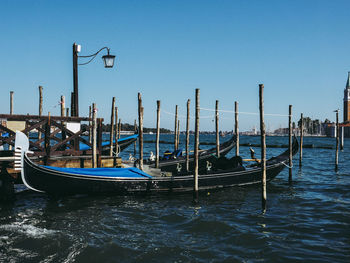 Boats moored in canal against clear blue sky