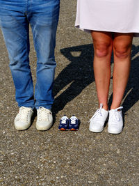 Low section of couple standing by baby booties on road