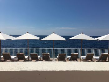 Chairs on beach against blue sky