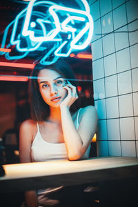 Portrait of young woman with hand on chin sitting in restaurant