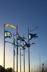 Low angle view of flags against clear blue sky