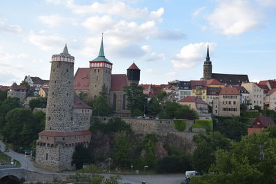 Buildings by river against sky in city