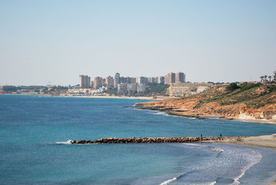 Scenic view of sea and buildings against clear sky