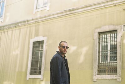 Portrait of man standing against building