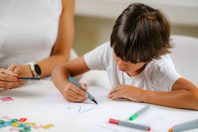 Boy writing letters on preschool screening test.