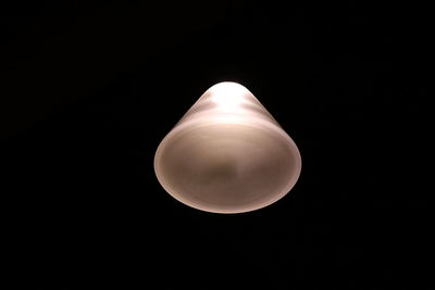 Close-up of illuminated light bulb over black background