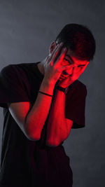 Side view of young man standing against black background