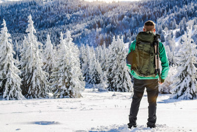 Rear view of man standing on snow covered land