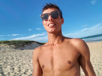 Portrait of shirtless man wearing sunglasses at beach