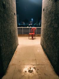 Illuminated walkway by wall in city at night