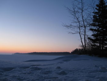 Scenic view of snowy landscape against clear sky during sunset