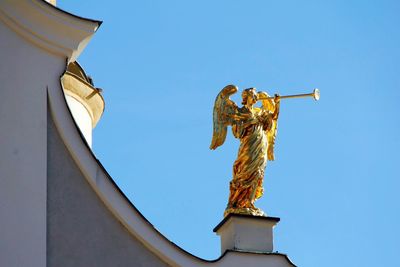 Low angle view of angel statue against clear blue sky