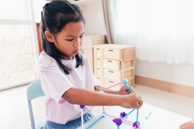 Cute asian child girl playing and creating with playdough and straws. 