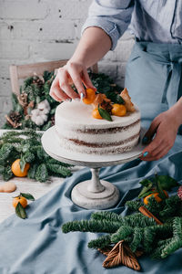 Midsection of woman decorating cake on table