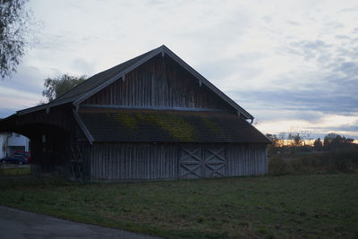 Barn on field by building against sky