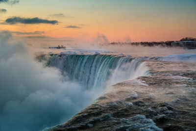 Scenic view of waterfall against sky at sunrise