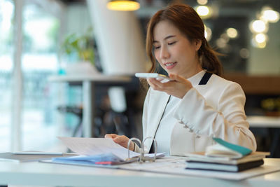 Woman looking at camera while sitting on table