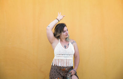 Portrait of happy spanish girl dancing flamenco dance against yellow wall