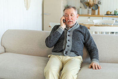 Portrait of young woman using phone while sitting on sofa at home