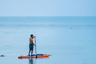 Rear view of man on sea against sky