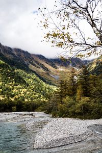 Scenic view of river by mountains against sky